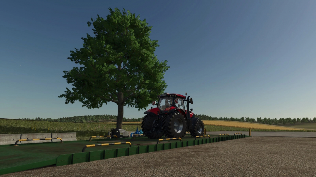 FS25 Washingarea mod: tractor on wash pad beside tree in Farming Simulator 25.