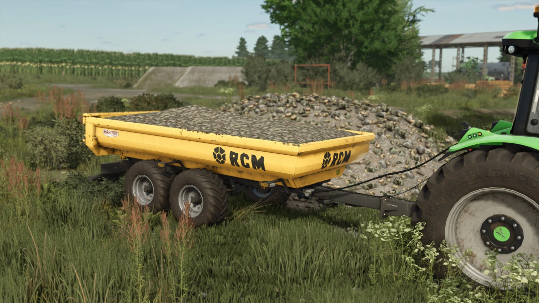 RCM PK1 mod in Farming Simulator 25, featuring a yellow trailer loaded with rocks in a rural field.