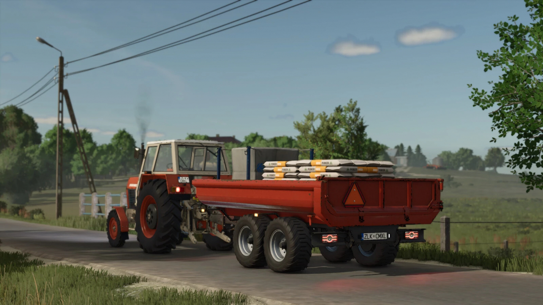 FS25 mod RCM PK1 v1.0.0.0 featuring a tractor with a red trailer carrying sacks on a rural road.