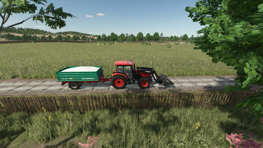 Farming Simulator 25 mod: tractor with a concrete plate 3m v1.0.0.0 on a farm road, with a green trailer, in a rural landscape.
