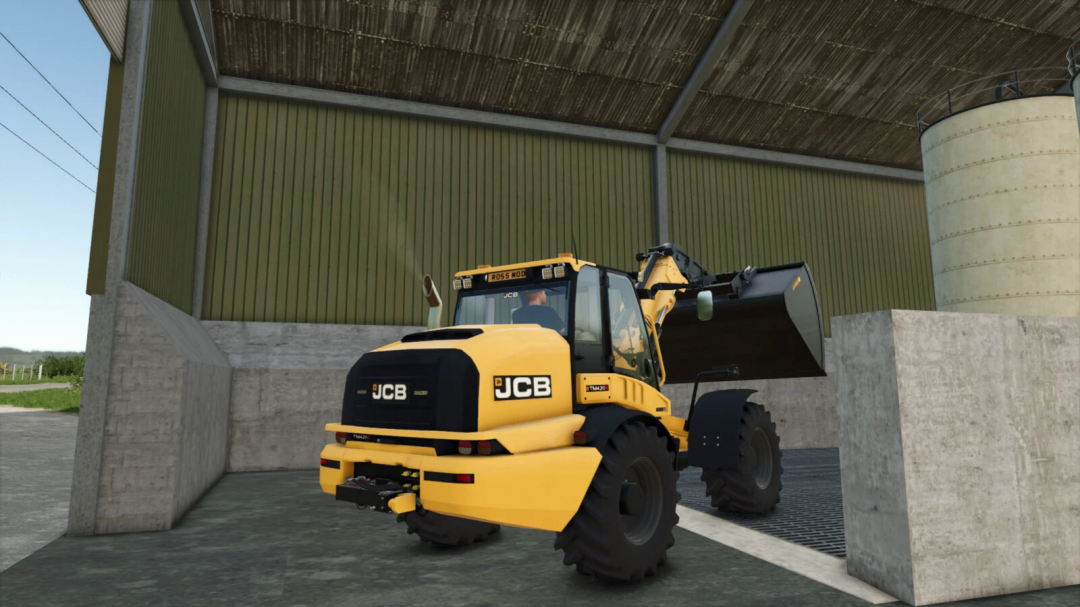 In Farming Simulator 25, a JCB TM 420S wheel loader mod is shown working inside a farm buildng with concrete walls and a large scoop.
