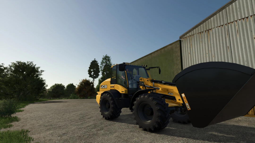 Farming Simulator 25 mod featuring a yellow JCB TM 420S wheel loader with a large bucket, parked near a warehouse in a rural setting.