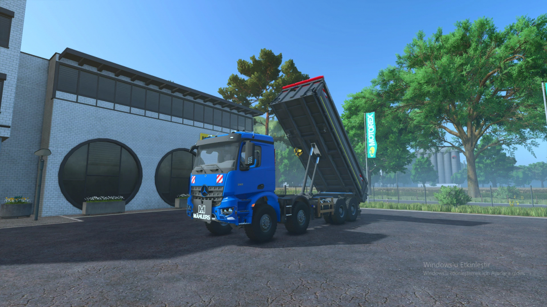 Farming Simulator 25 mod: Mercedes Arocs 8x8 dump truck with raised bed, blue cab, parked outside a building, in a rural setting.