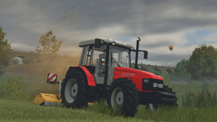 fs25-mods, Farming Simulator 25 mod: Red SDF Silver 105 tractor with mowing attachment in a lush field with trees and a bridge in the background.