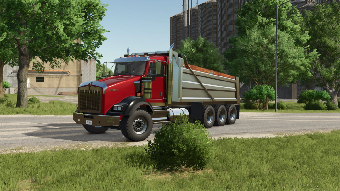 Farming Simulator 25 mod: Red Kenworth T800 dump truck on a rural road with trees and industrial buildings in the background.