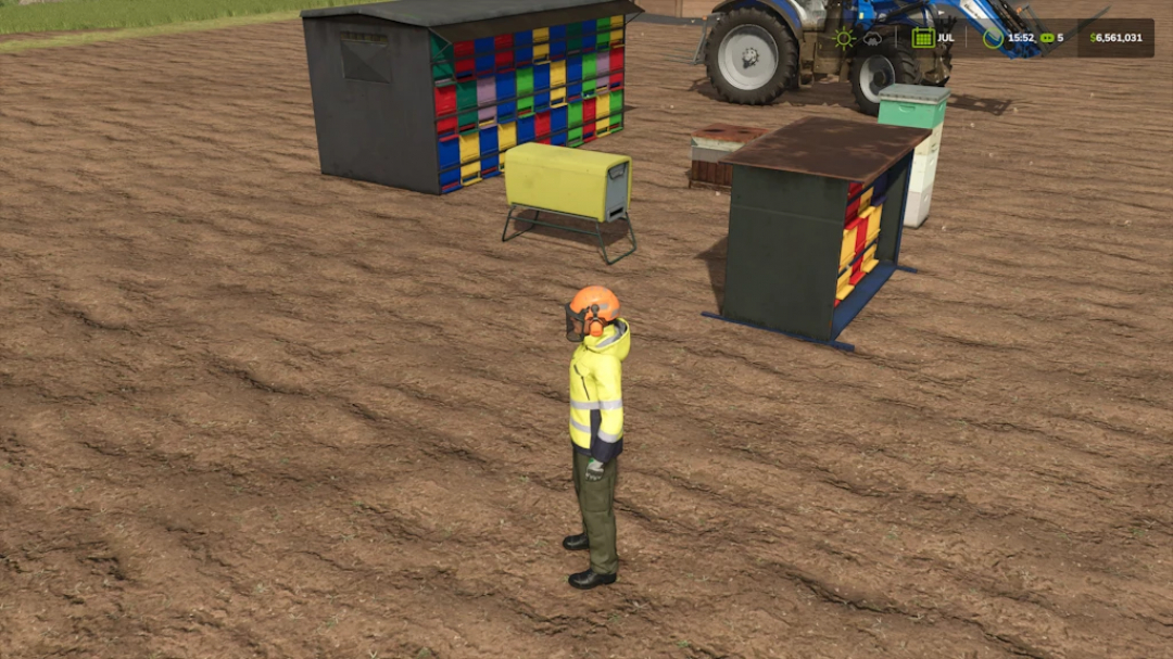 Farming Simulator 25 mod image showing a worker in protective gear standing on plowed soil next to colorful storage containers and a tractor.