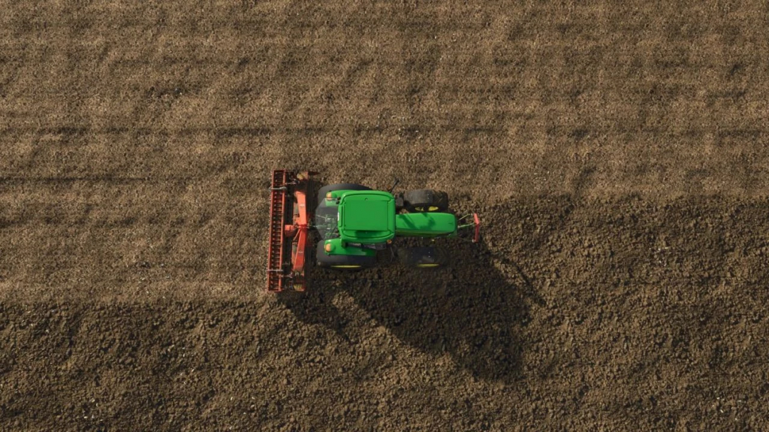 A green tractor working on a plowed field, showcasing Farming Simulator 25 mods with ground textures.