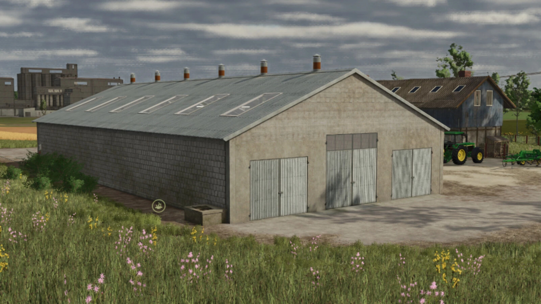 Farmers view of the Big Cow Barn mod in Farming Simulator 25, featuring a large barn with metal doors and a field with wildflowers in the foreground.