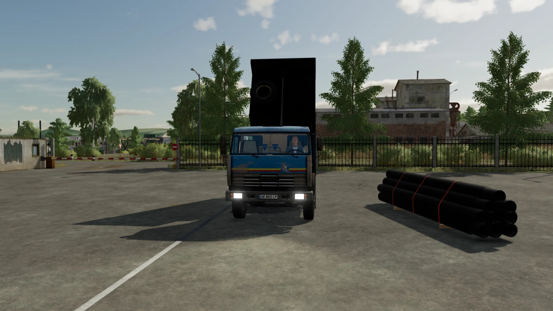 Farming Simulator 22 mod: KamAZ 65115 truck with loudspeaker, parked next to black pipes, in a rural yard.