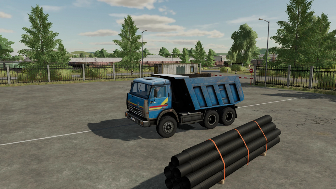 FS22 mod: Blue KamAZ 65115 dump truck with black pipes, parked on a concrete lot with trees and fence in the background.