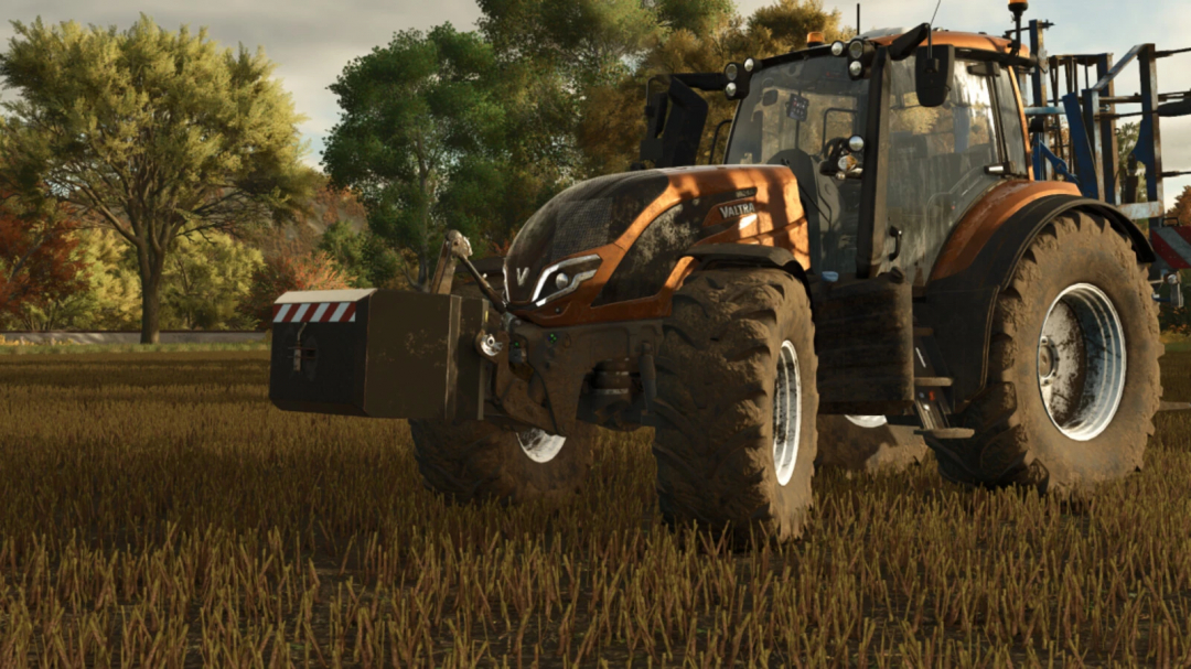 Farming Simulator 25 mod: Valtra tractor with Koja Weight Pack v1.0.0.0 on a farm field with trees in the background.
