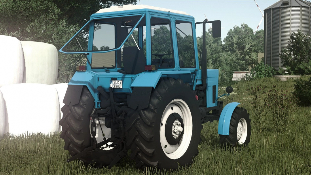 Farming Simulator 25 mod: Blue MTZ 82 tractor with large rear tires and enclosed cab, shown on a farm field with hay bales in the background.