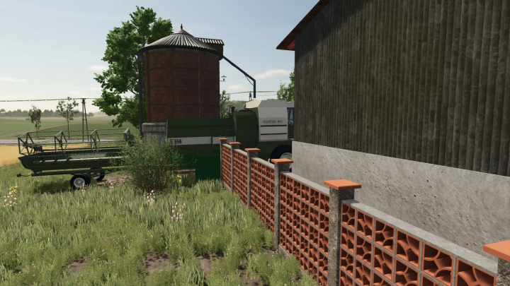 fs25-mods, In Farming Simulator 25, a brick fence and metal gate from the FS25 mods pack next to a farm building with a silo and agricultural equipment.