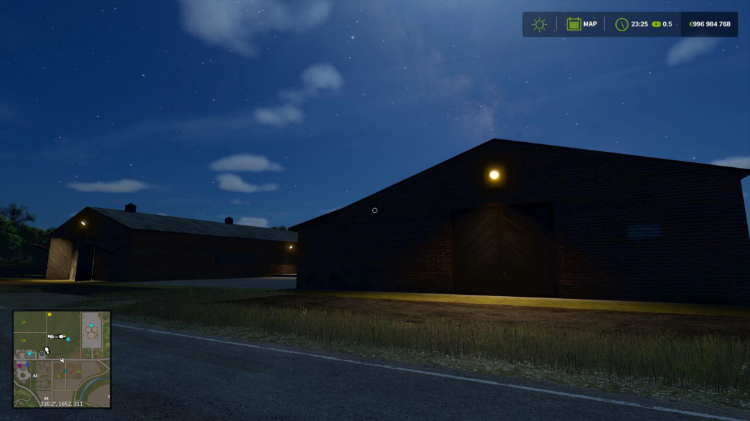 Nighttime view of a dark barn in Farming Simulator 25 with lights on and a map overlay in the corner.