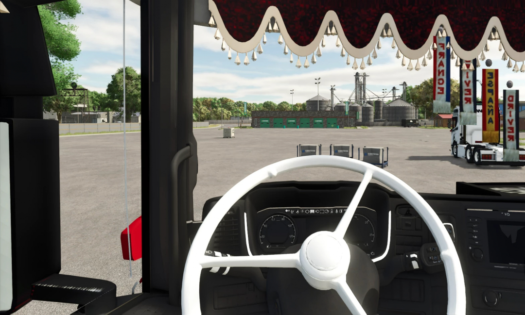 View from the truck cab in Farming Simulator 25 with a focus on the dashboard and outside yard featuring carnival rides and equipment mods, including the SCANIA T v1.0.0.0.