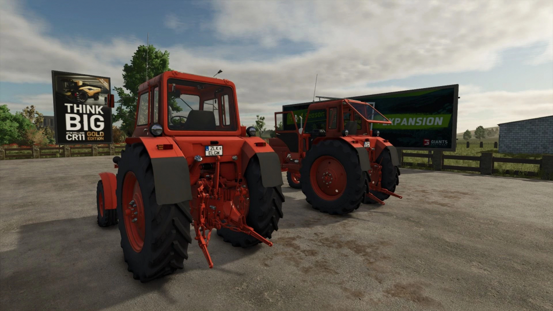 Two red tractors from Farming Simulator 25 mods parked outdoors with billboards in the background.
