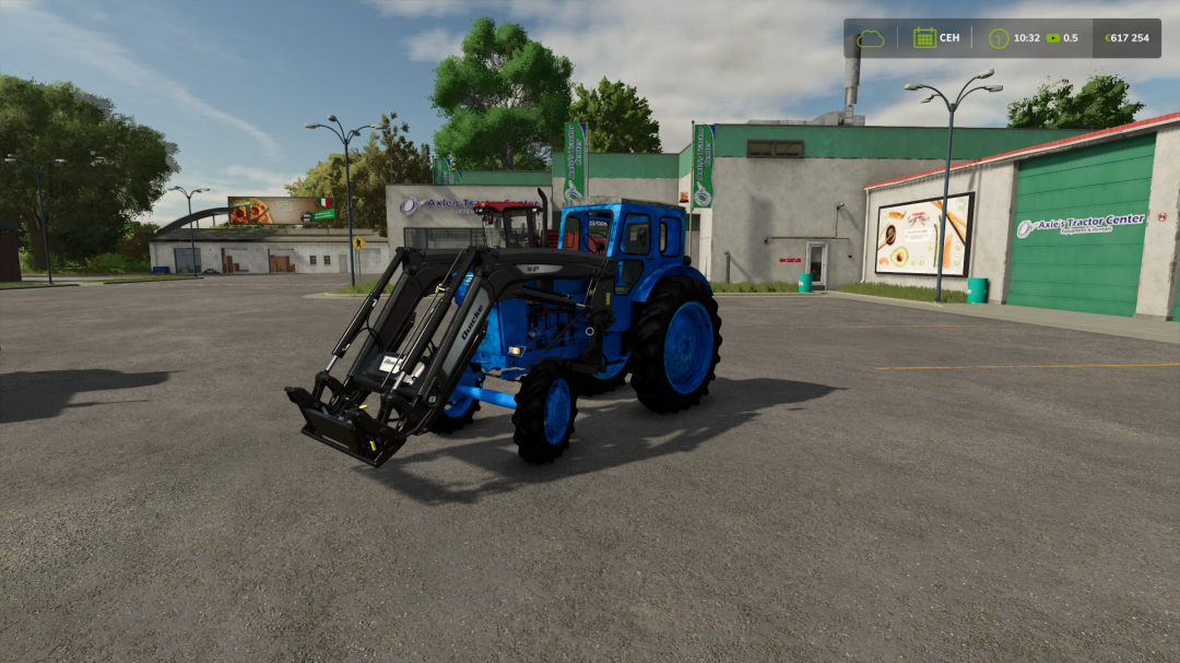 FS25 mod: Blue tractor with front loader attachment parked outside Axle's Tractor Center in Farming Simulator 25.