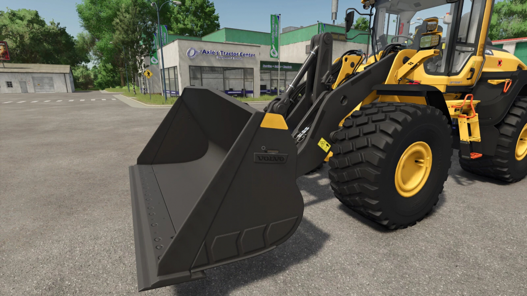Farming Simulator 25 mod: yellow wheel loader with black Volvo bucket, parked on the street near a tractor equipment center.