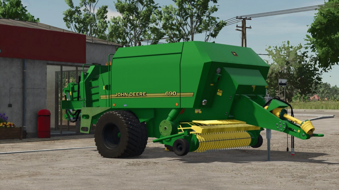 Farming Simulator 25 mod: John Deere 690 baler in a farmyard setting, green with yellow accents, ready for hay collection.