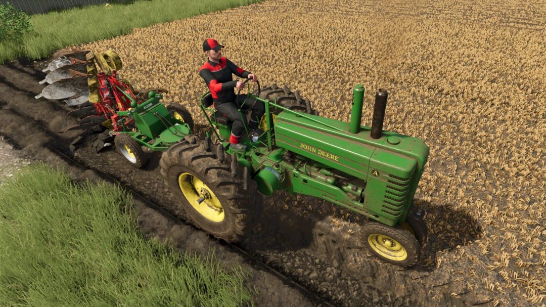Farming Simulator 25 mod: John Deere tractor pulling a plow, working in a wheat field with green grass beside the field.