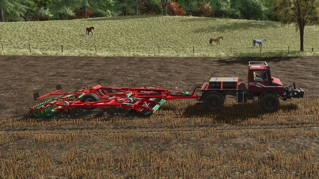 Farming Simulator 25 mod: a red tractor with a cultivator attached, working on a field with a green, autumn landscape and horses in the background.