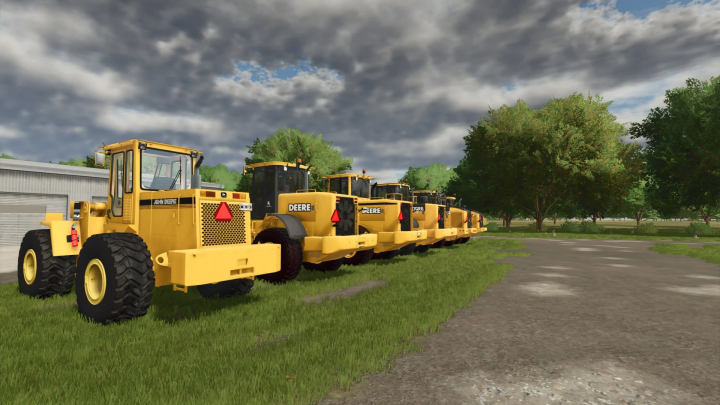 fs25-mods,  Line of yellow John Deere construction loaders in Farming Simulator 25 with trees and cloudy sky in the background.