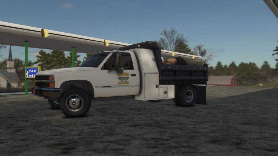 FS25 mods: Construction truck with equipment, parked near a pipeline at a gas station in Farming Simulator 25.