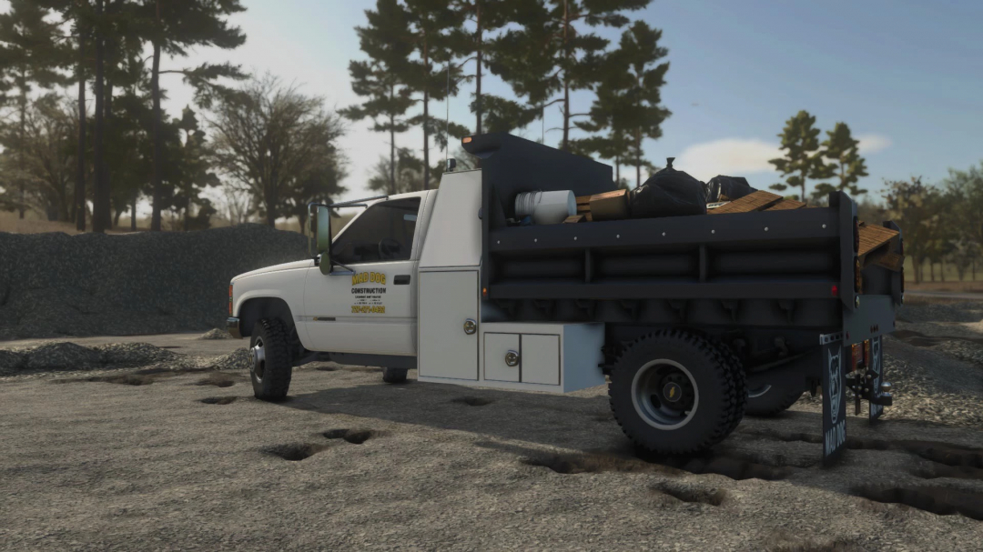 Farming Simulator 25 mod: construction flatbed pickup truck loaded with tools and supplies, in a dirt lot with trees in the background.