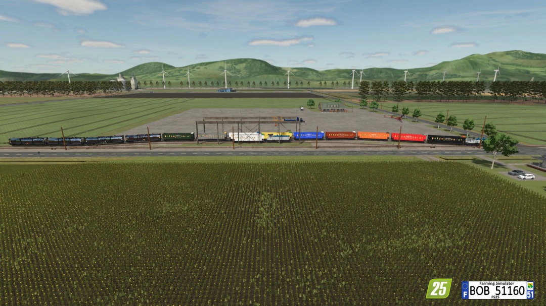 Farming Simulator 25 mod: Colorful grain train parked with wind turbines and green fields in the background, showcasing the Grain Wagon (ZCA Trains) v2.0.0.0.