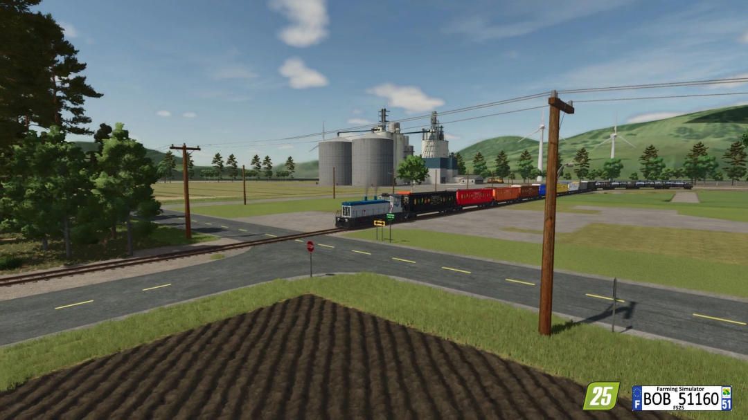 Farming Simulator 25 mod: colorful train crossing a rural area with grain silos in the background.