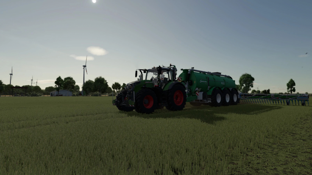 Farming Simulator 25 mod featuring a green tractor attached to a large green slurry tank in a rural field with wind turbines in the background.